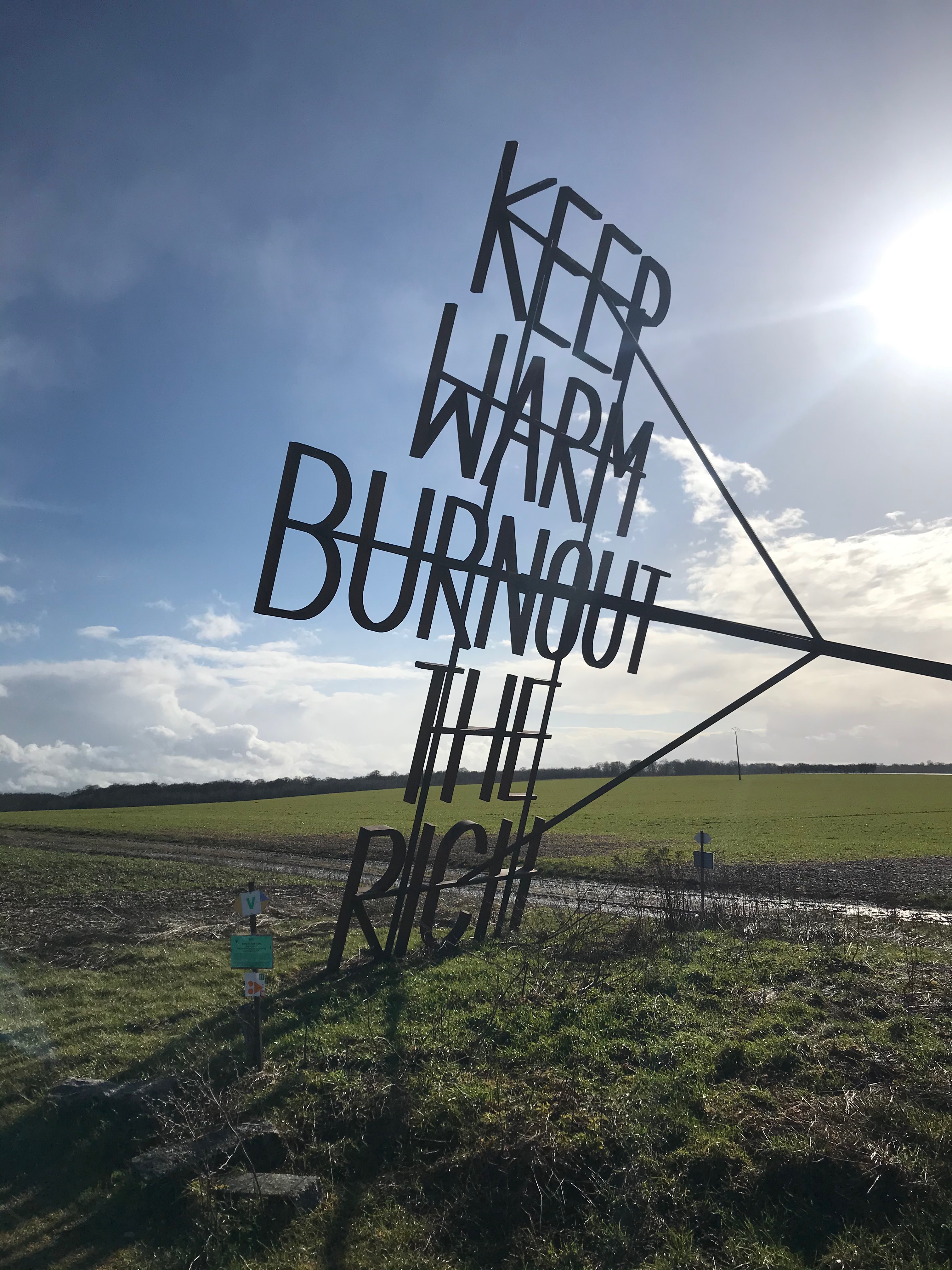 Oeuvre en forme de grand fer à marquer, intitulée "Keep warm, burn out the rich"