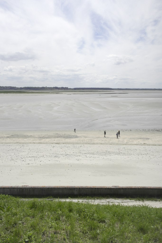 grande étendue de sable entre deux rives, des promeneurs sont sur le sable