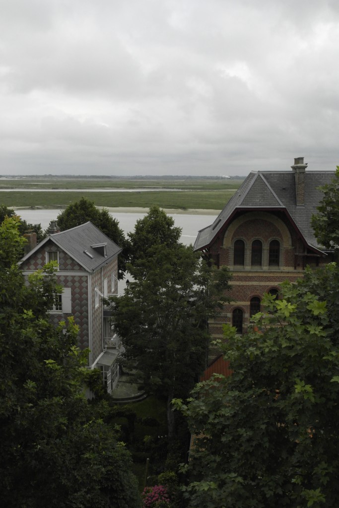 deux belles maisons en premier plan au milieu des arbres et au fond la baie de somme, entre eau et terrain enherbé
