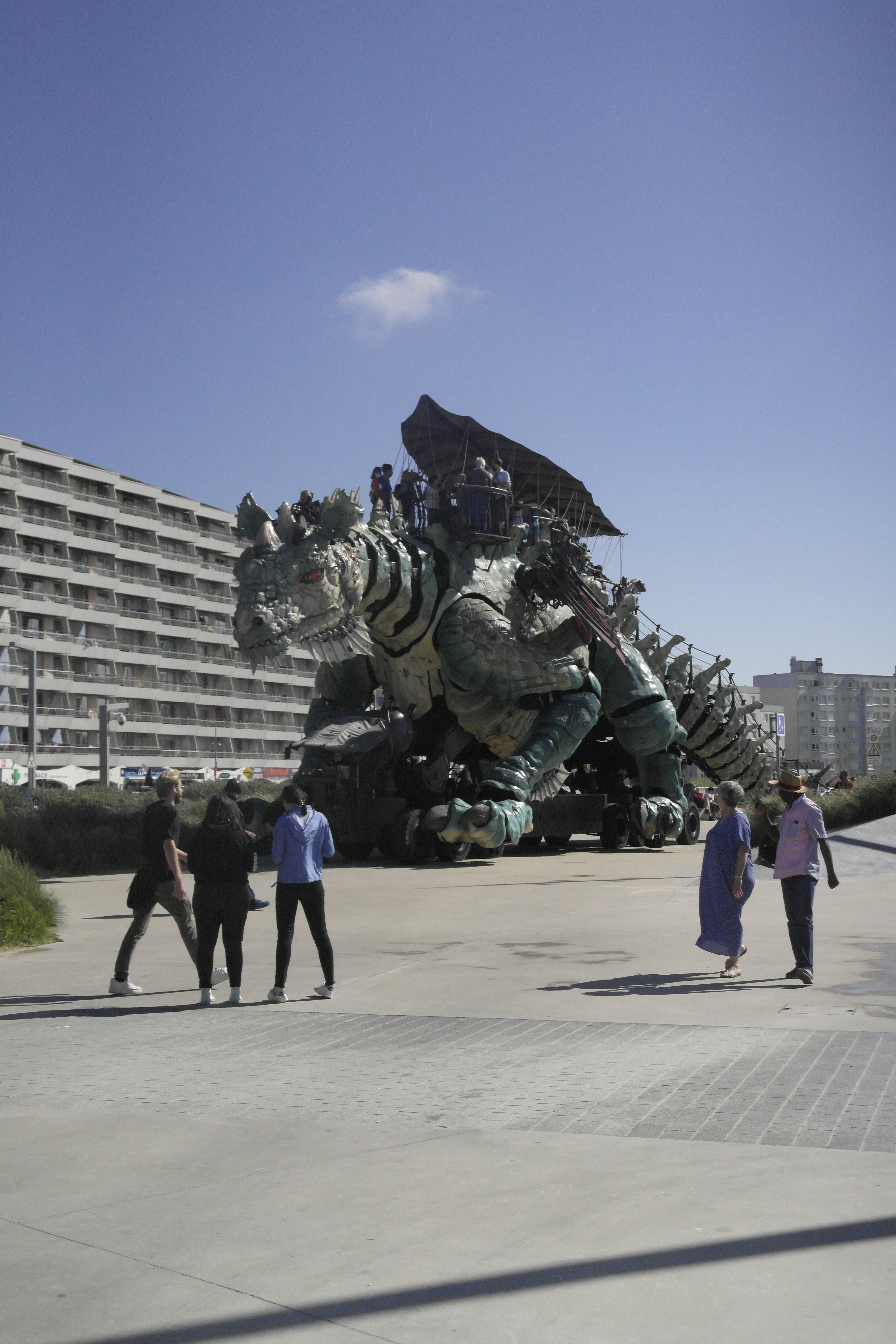 dragon articulé sur l'esplanade devant la mer à Calais, les passants regardent amusés