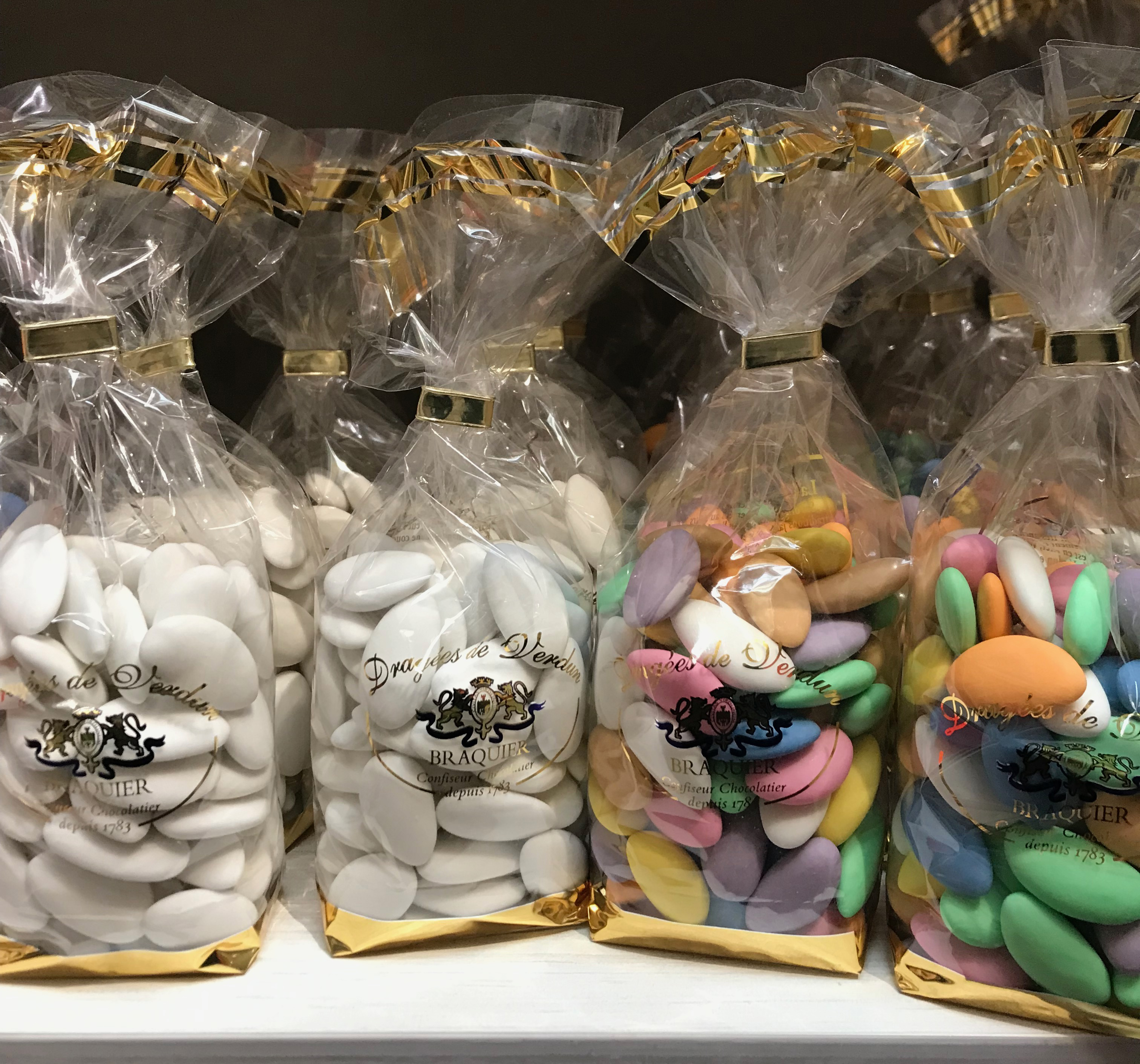 4 ballotins de dragées, estampillés Dragées Braquier, deux sont des dragées blanches, deux sont multicolores.