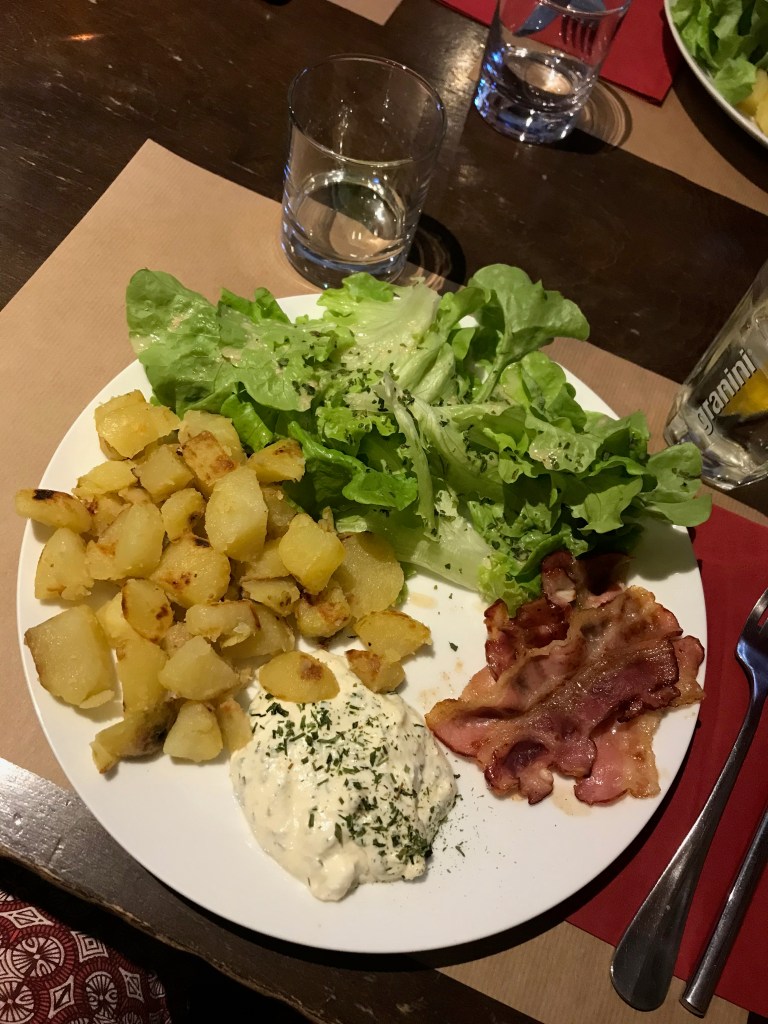 assiette composée de pommes de terre, sauces aux herbes, lards et salade