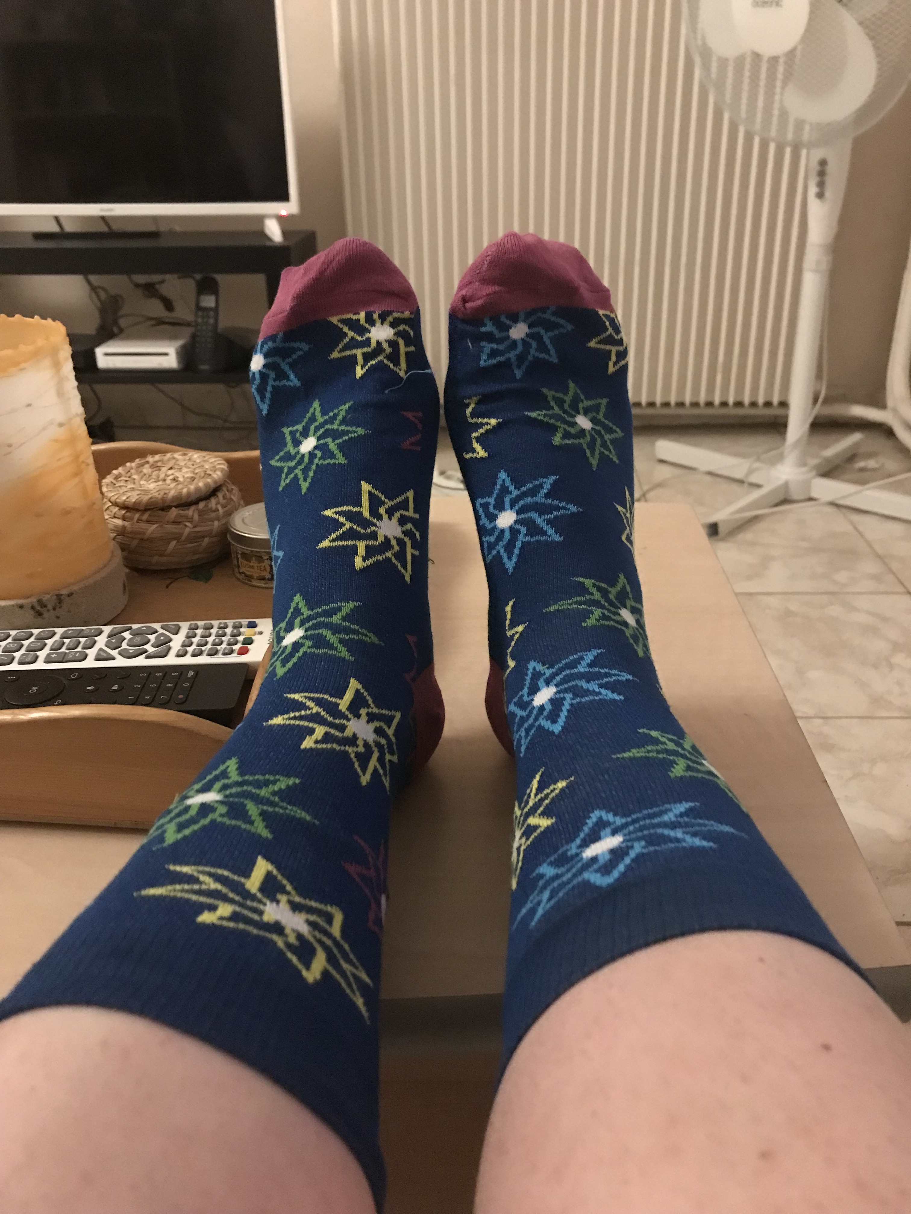 photos de pieds avec chaussettes bleues ornées de fleurs/étoiles jaunes, vertes, et bleus clairs