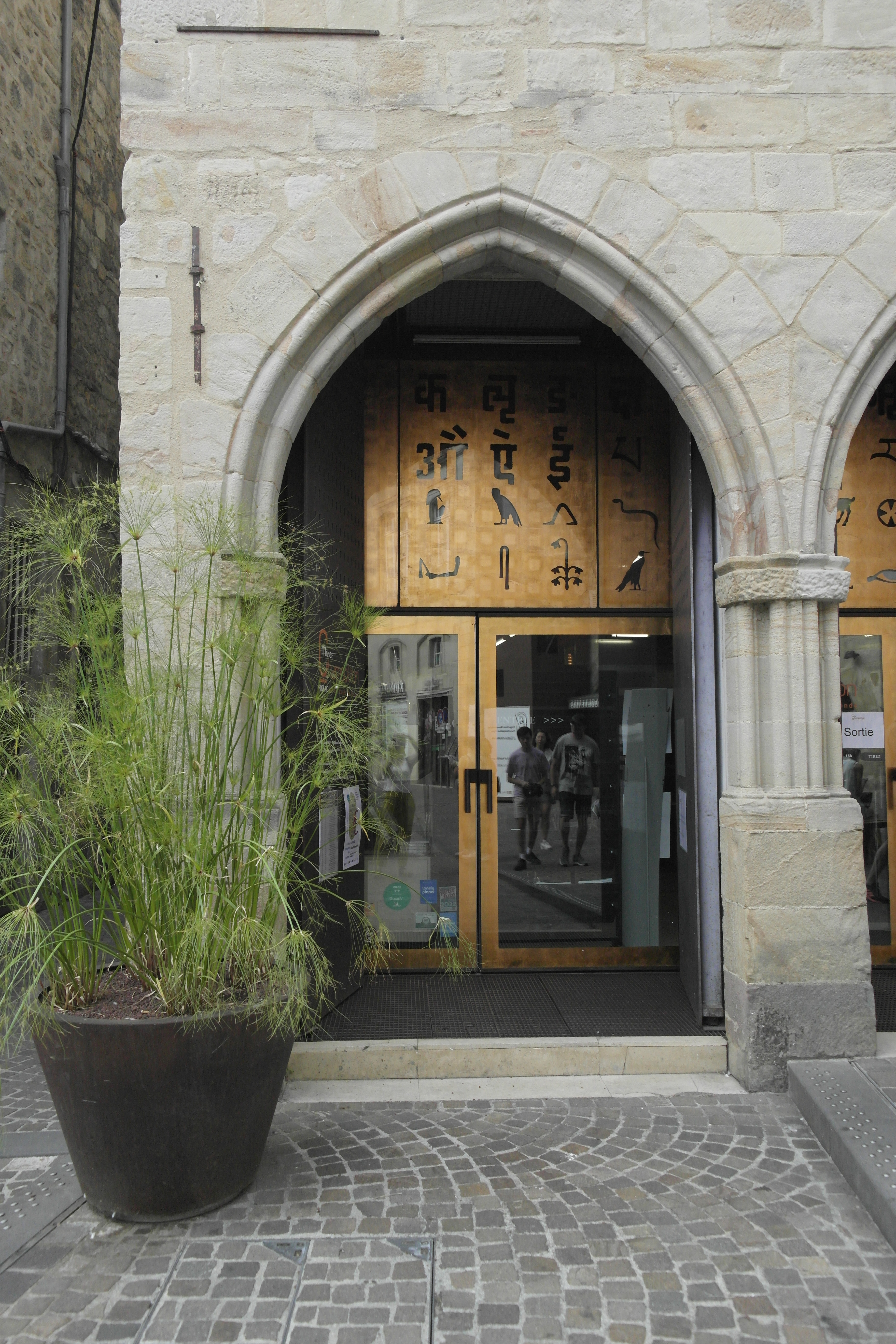 détail de façade, un arc brisé et à l'arrière, la double peau corten avec des hiéroglyphes