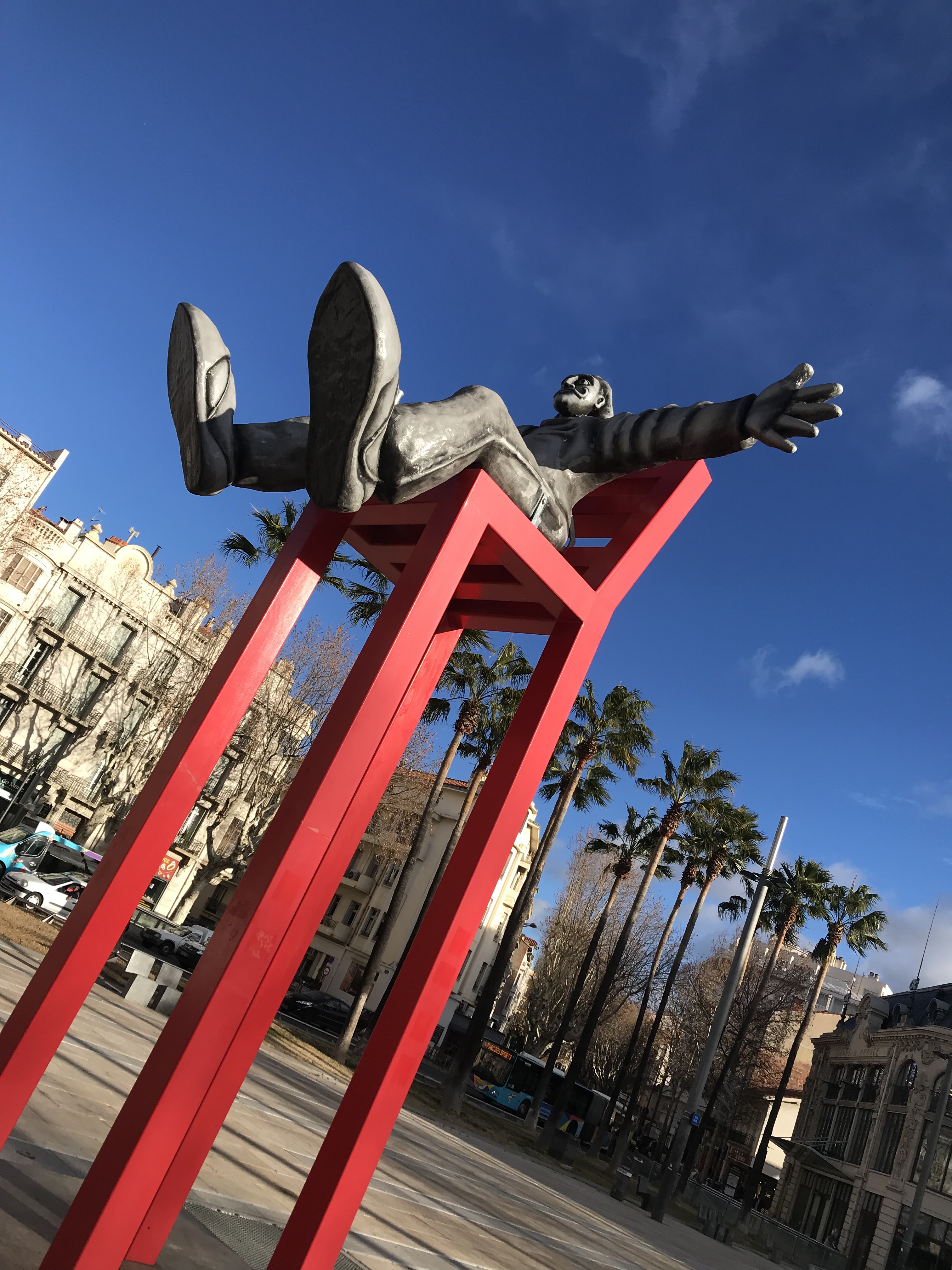 sculpture de Dali sur une chaise haute rouge, palmiers à l'arrière