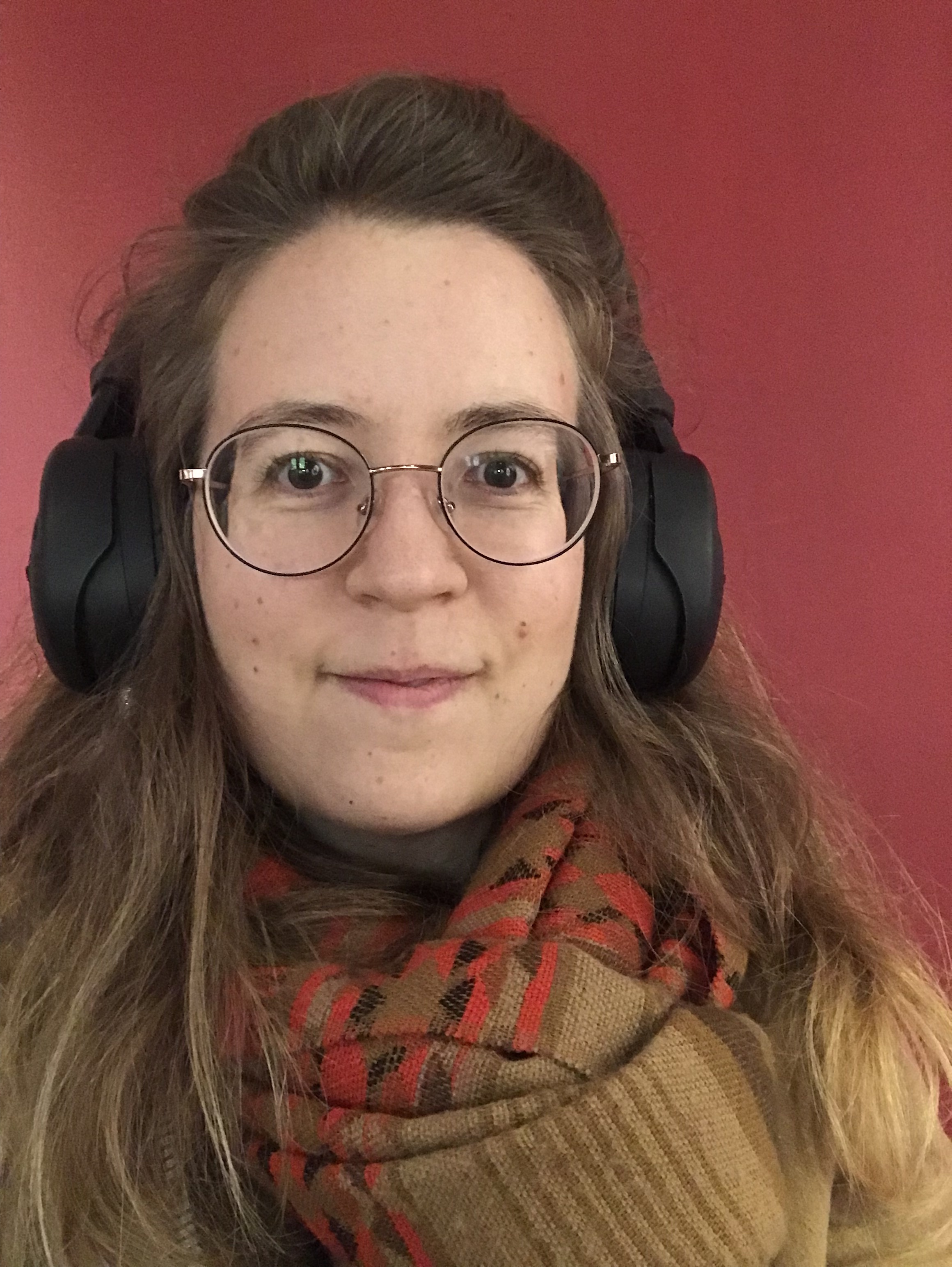 femme avec casque sur les oreilles, sourire, fond rouge