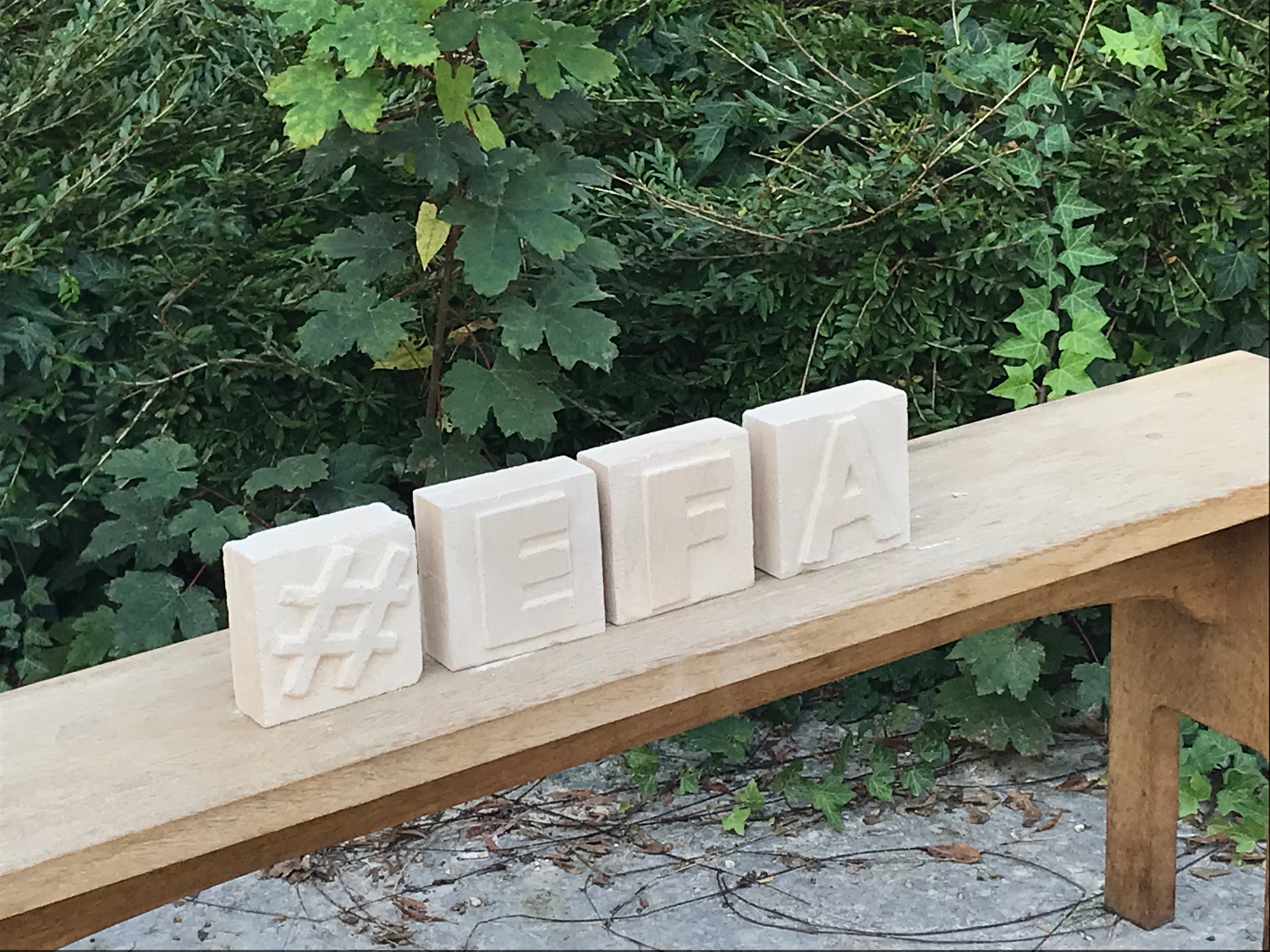 4 blocs de pierre carrés avec un hashtag et les lettres EFA gravées dessus