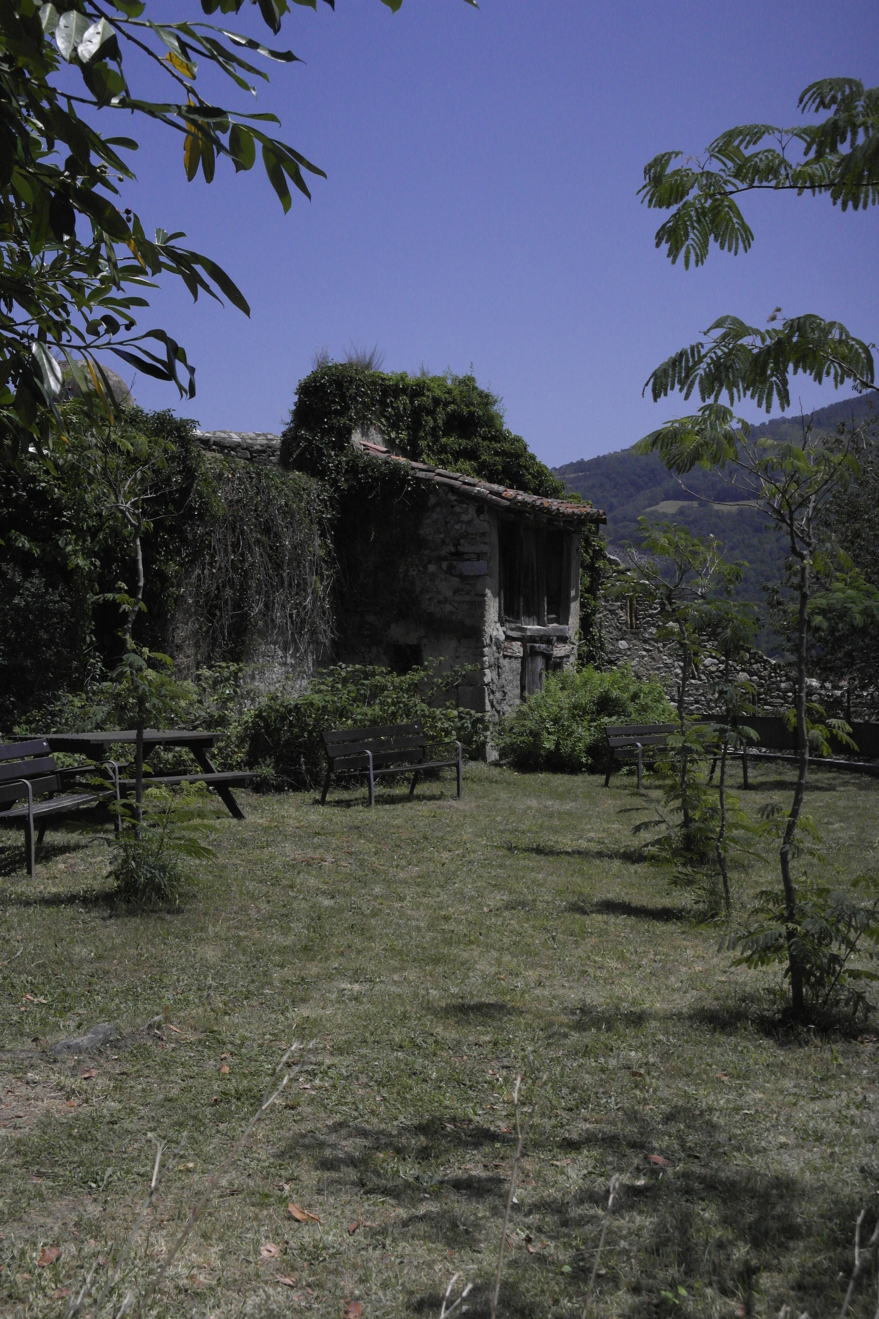 jardin avec gazon, tables de pique-nique, et bâtiment en pierre en ruines