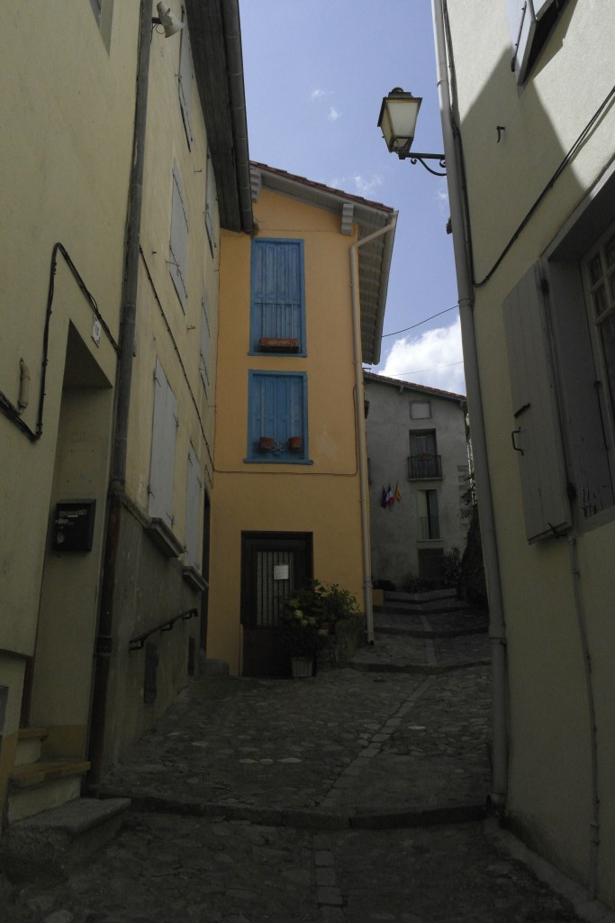 ruelle en pente, maison jaune à volets bleus