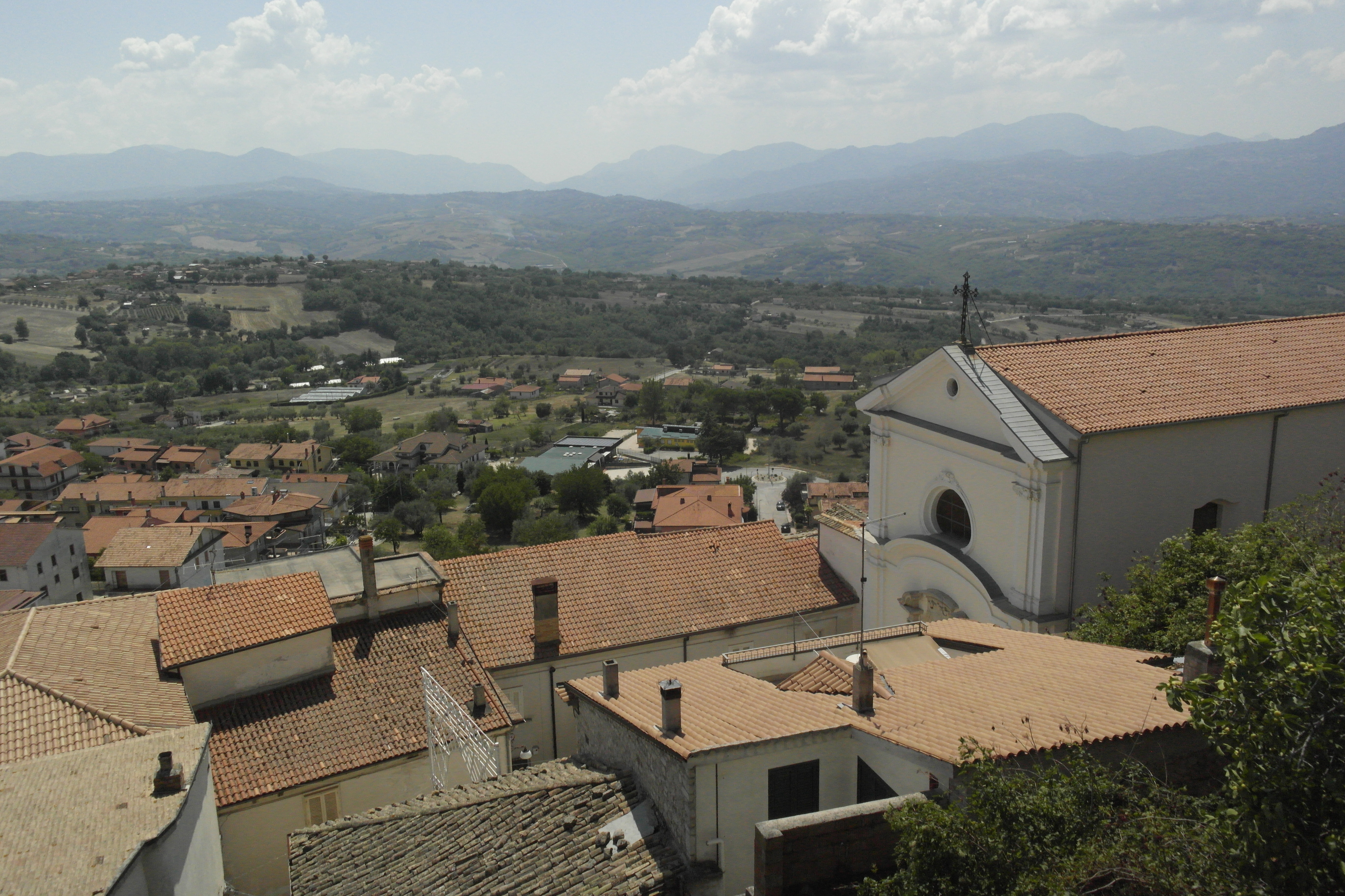 vue d'un village en contrebas et des montagnes au fond, au bout de la vallée