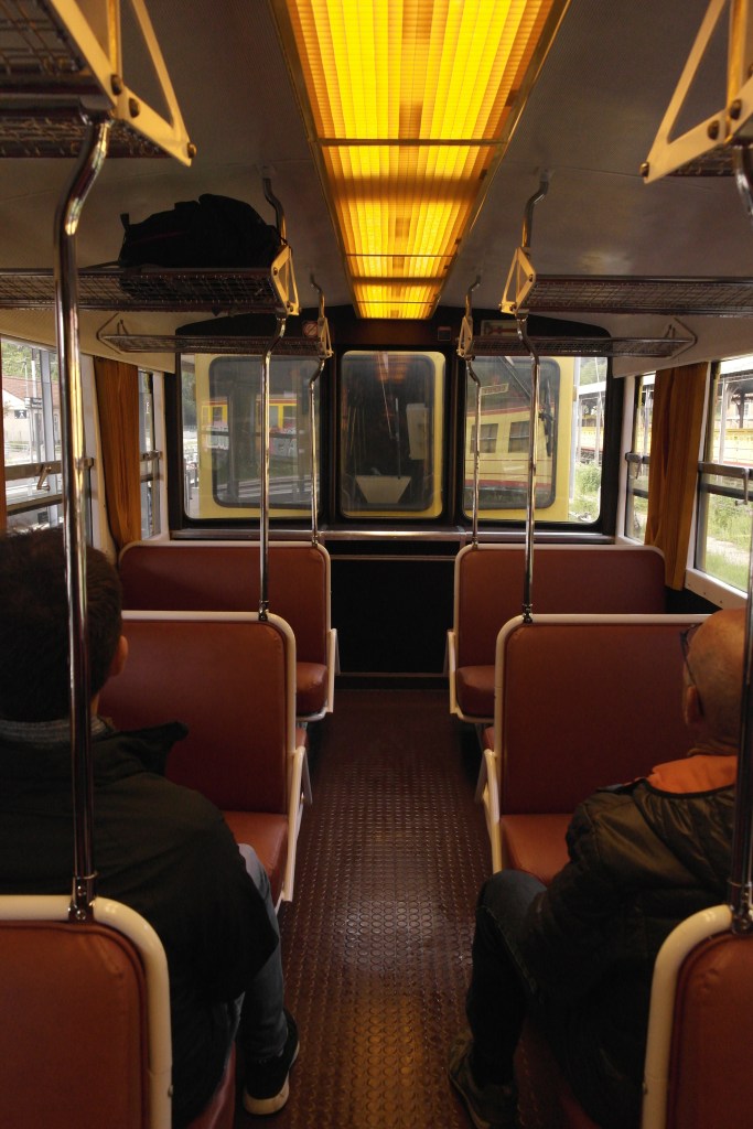 intérieur du train jaune, rangées de sièges rouges