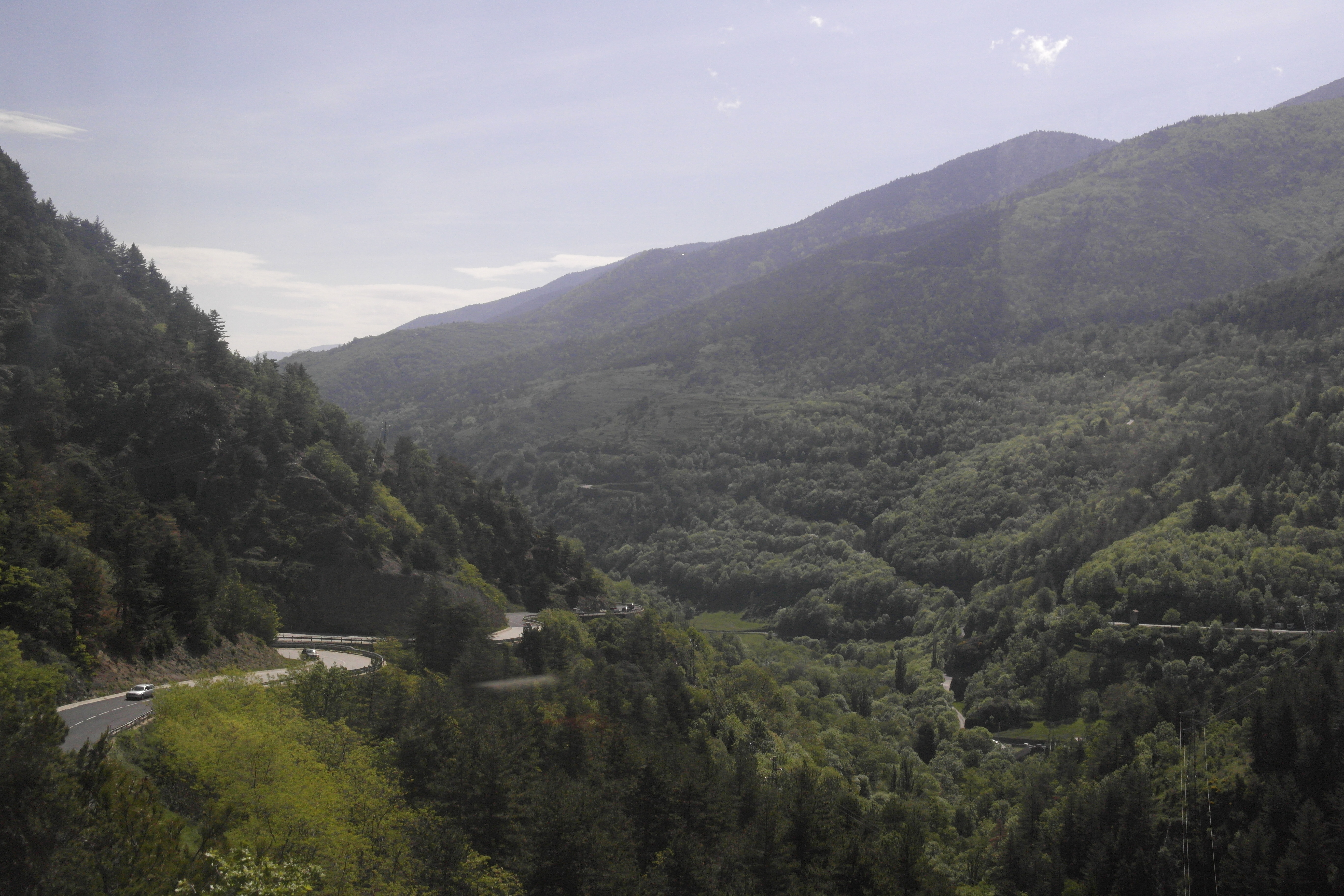 montagnes recouvertes de végétation, route vue d'en haut, ciel bleu