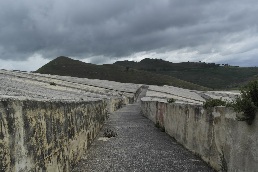 Creto di Burri à Gibellina : rue entre deux blocs de béton et forêt au loin.